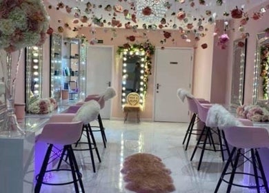 Elegant beauty salon interior at HMAKE, Stockport, England, GB with pink chairs and floral decor.