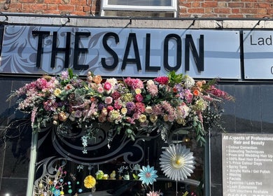 The Salon in Wigan, GB with vibrant floral decorations adorning the entrance sign.