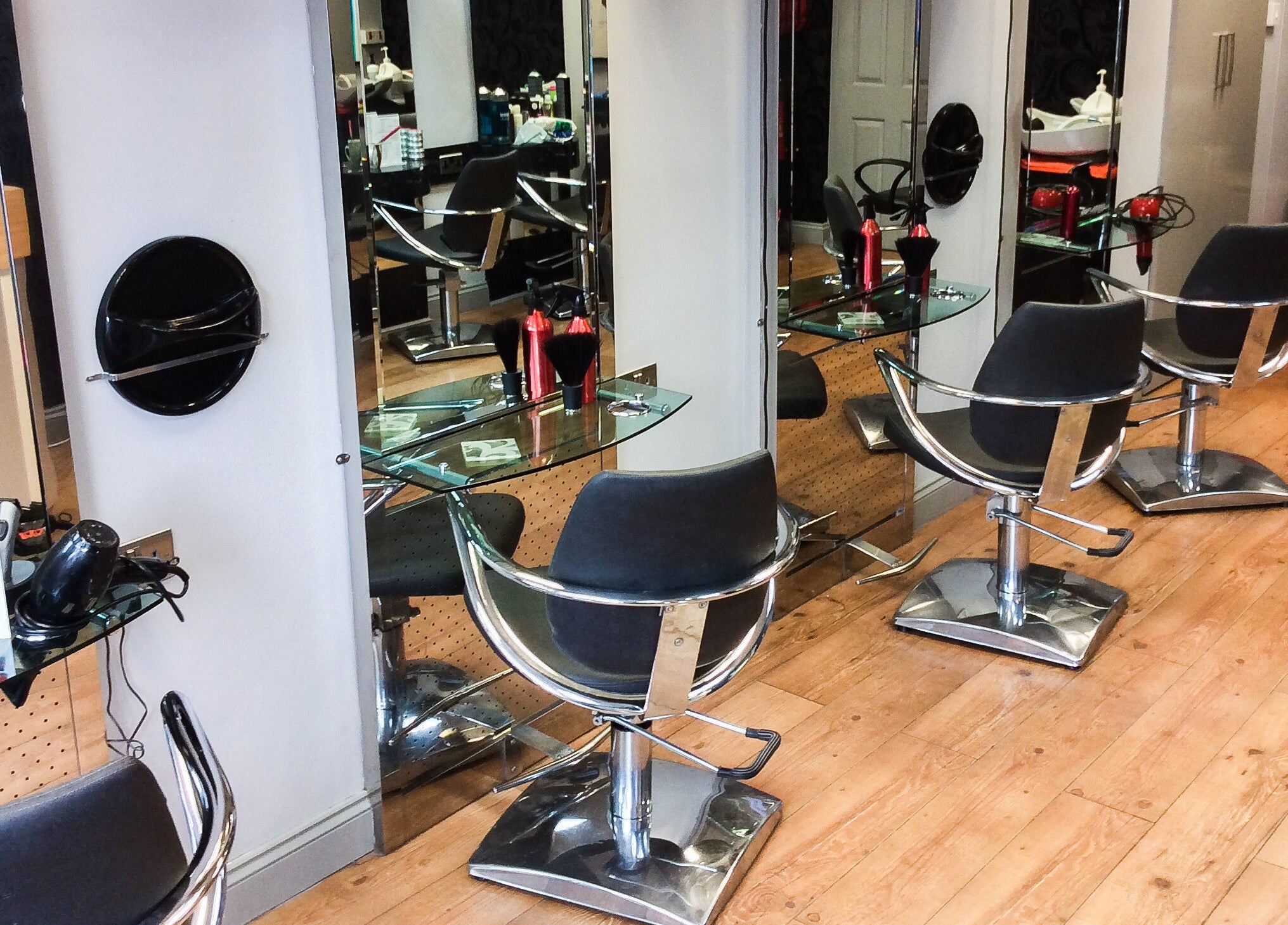 Modern styling stations at The Salon, Wigan, GB showcasing sleek chairs and shiny mirrors.