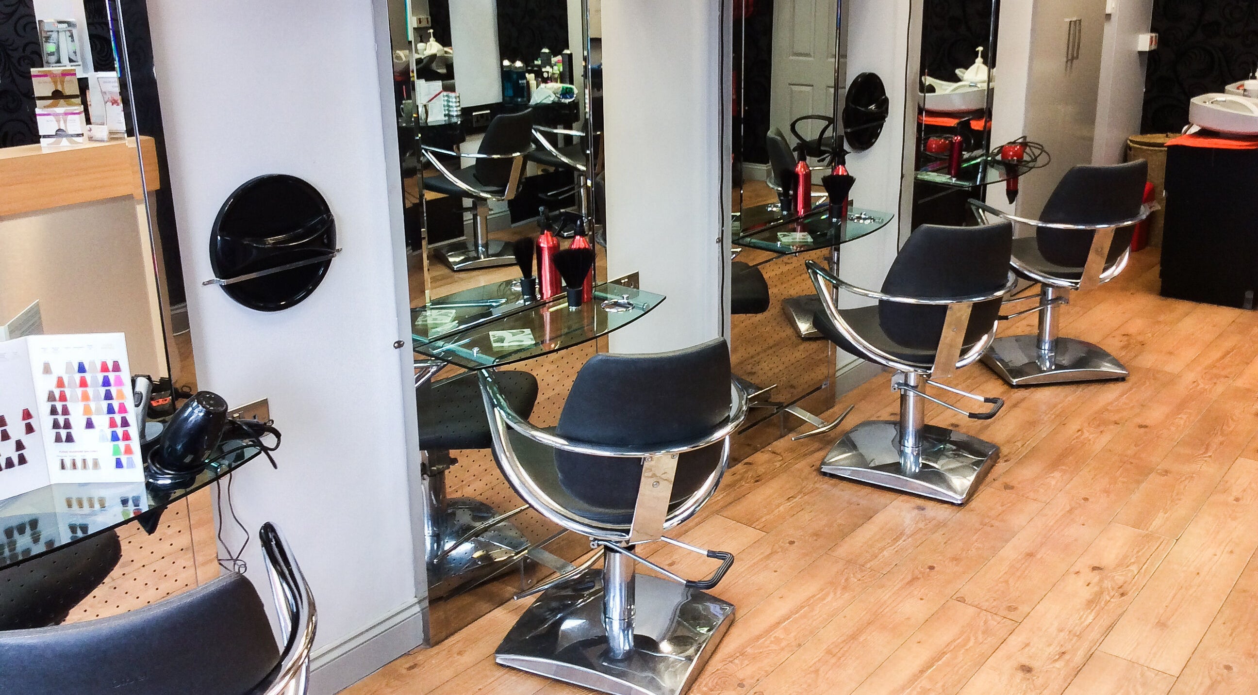 Modern styling stations at The Salon, Wigan, GB showcasing sleek chairs and shiny mirrors.