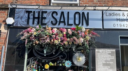 The Salon in Wigan, GB with a vibrant floral display adorning the entrance sign.