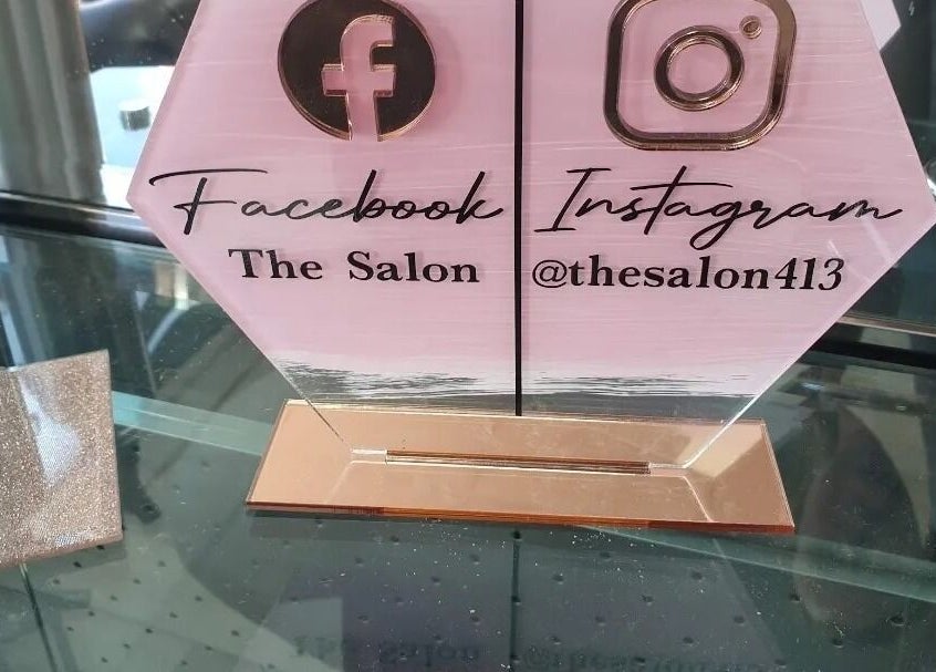 The Salon's social media sign in Wigan, GB showcasing Facebook and Instagram details.