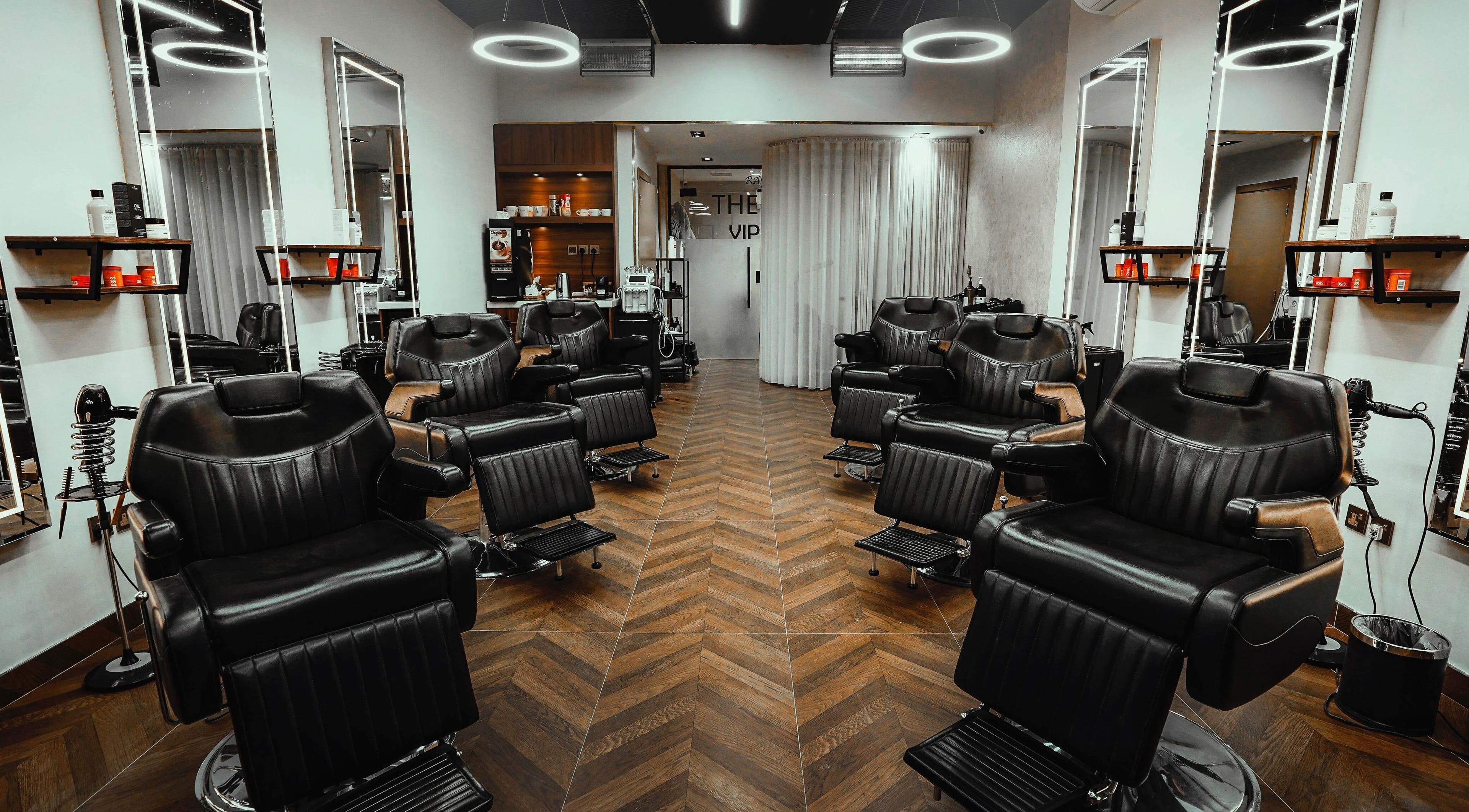 Sleek interior of The Artist Barber in الرياض, منطقة الرياض, SA with modern chairs and lighting.