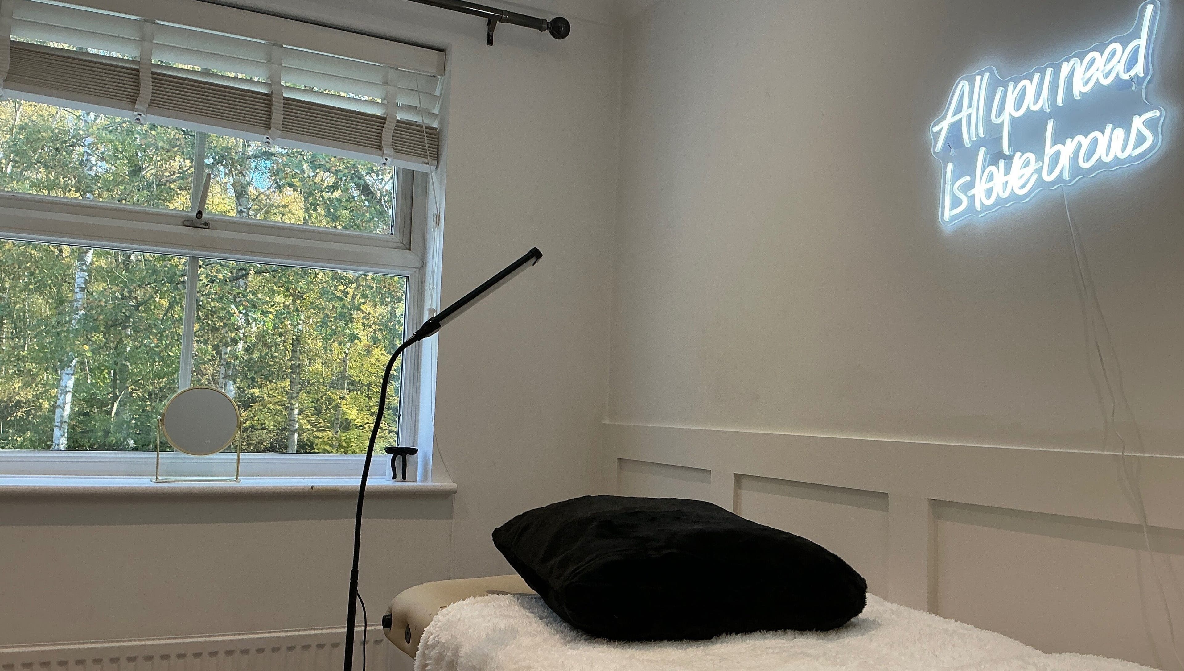 Cozy interior of Brows by Lauren in Lincoln, England, GB, featuring a neon sign and comfortable treatment bed.