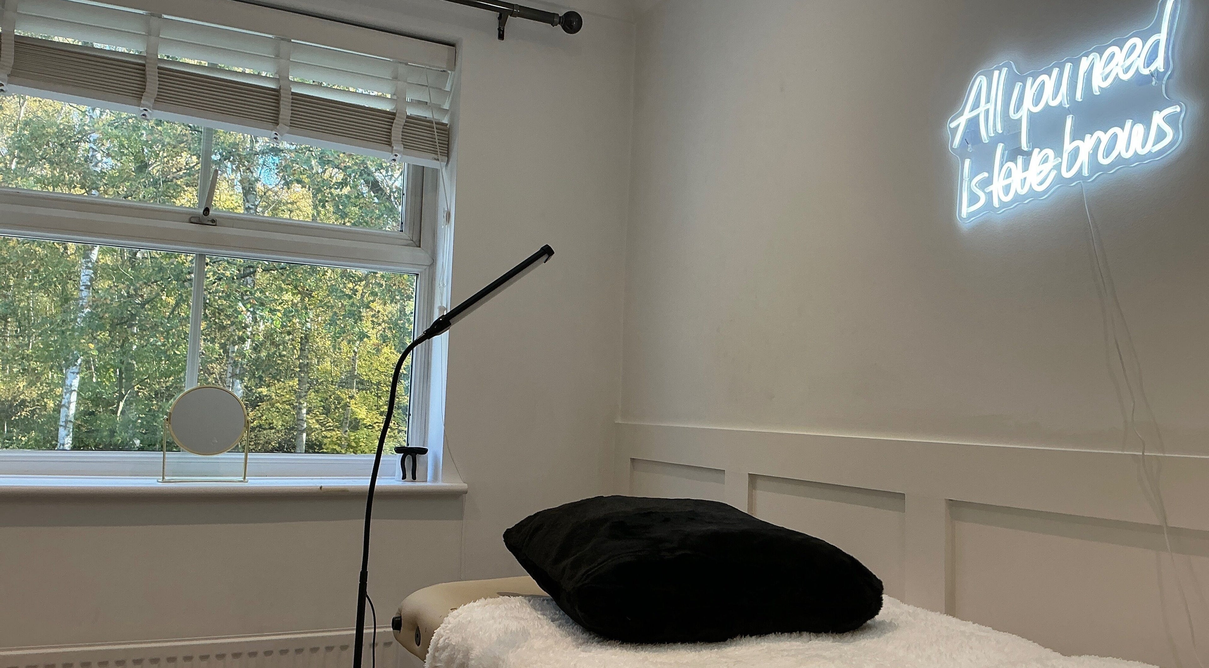 Cozy interior of Brows by Lauren in Lincoln, England, GB, featuring a neon sign and comfortable treatment bed.