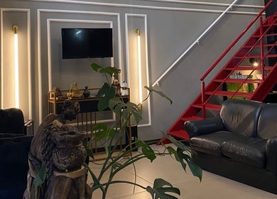 Interior elegante do Kurotake Barbershop em Paraná, Paraná, BR, com sofá preto e escada vermelha.