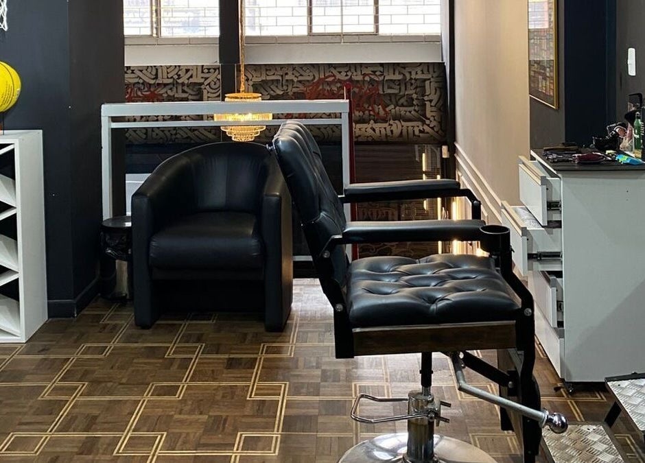 Interior moderno da Kurotake Barbershop em Paraná, BR, com cadeiras de couro e decoração sofisticada.
