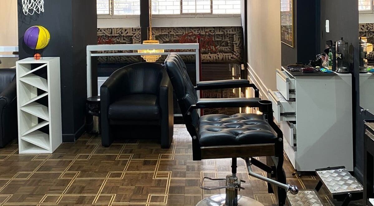 Interior moderno da Kurotake Barbershop em Paraná, BR, com cadeiras de couro e decoração sofisticada.