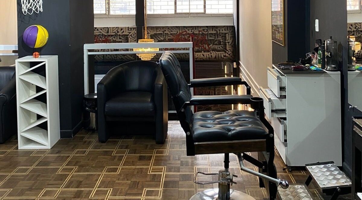 Interior moderno da Kurotake Barbershop em Paraná, BR, com cadeiras de couro e decoração sofisticada.