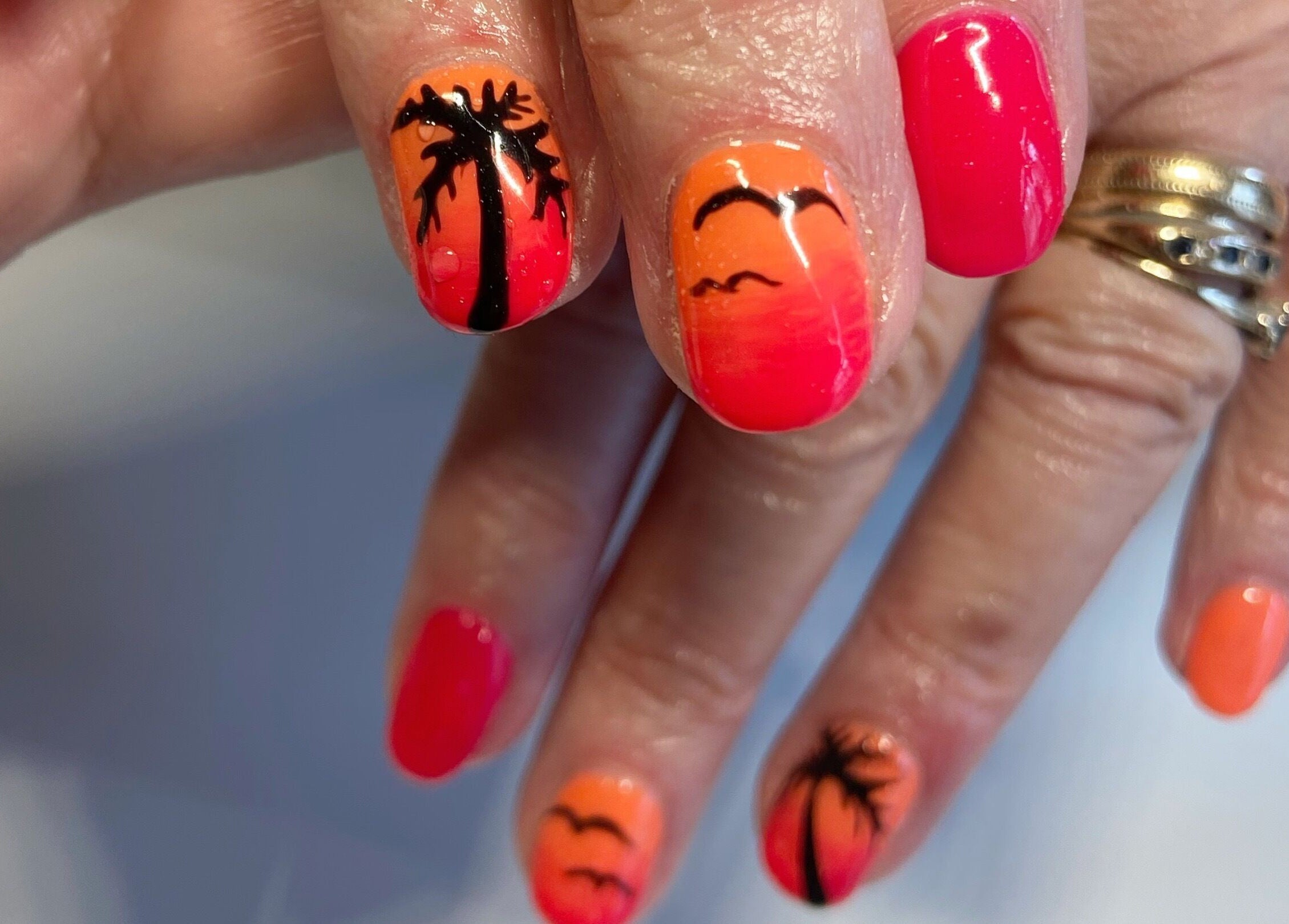 Vibrant tropical nail art at Nails By Jo, Fremington, England, GB, showcasing palm trees and orange hues.