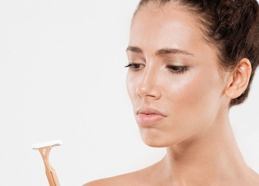 Woman contemplates beauty tool at Beautiology, Auckland, Auckland, NZ, enhancing natural skin glow.