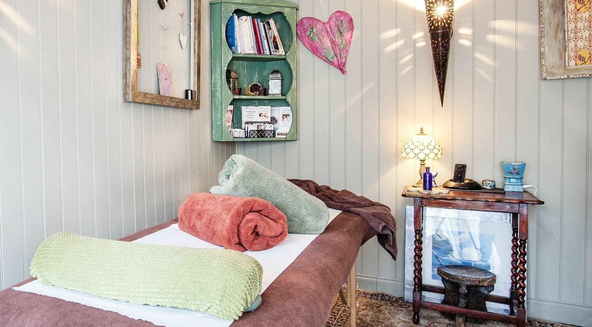 Cozy treatment room at Nafisa ~ Transformational BodyWorker in Teddington, GB, featuring elegant decor and plush towels.