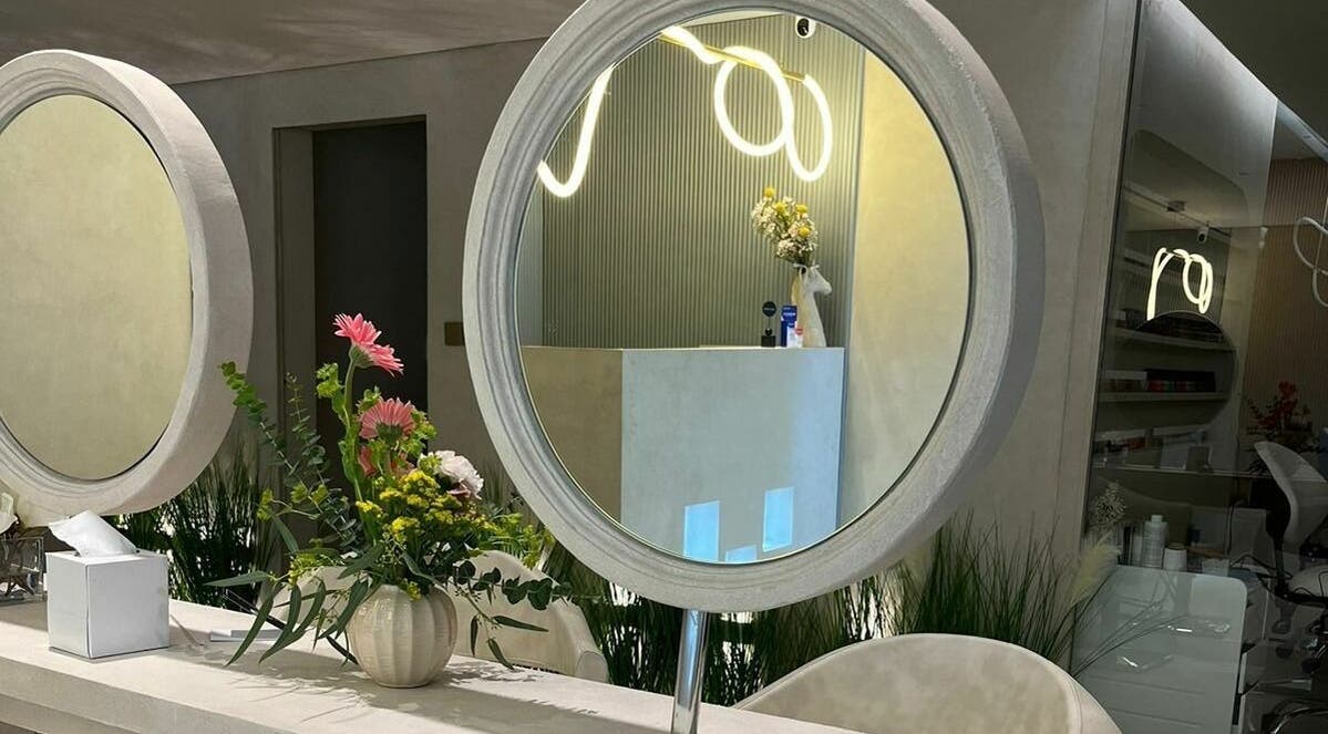 Elegant interior view of Jaw Beauty Salon, Abu Dhabi, AE with round mirror and floral decor.