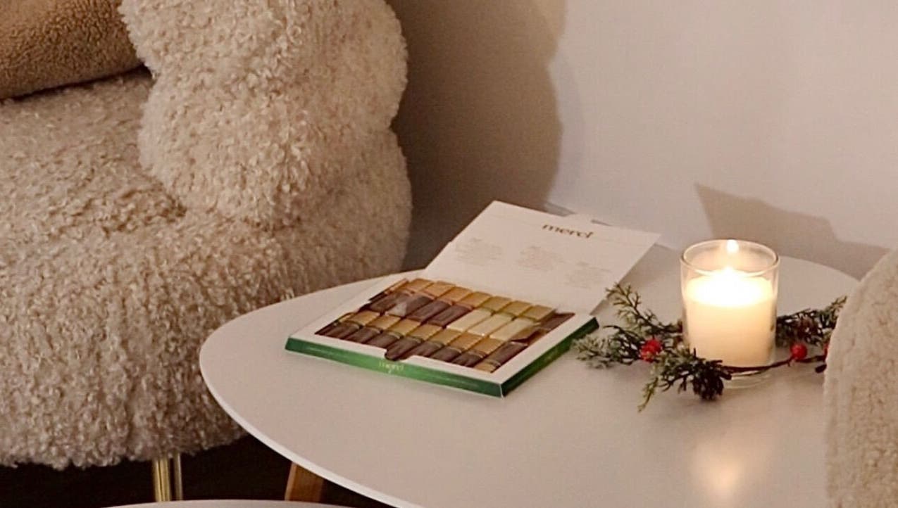 Udoban kutak u Rituals Nails, Beograd, RS s plišanom stolicom i svijećom na stolu.