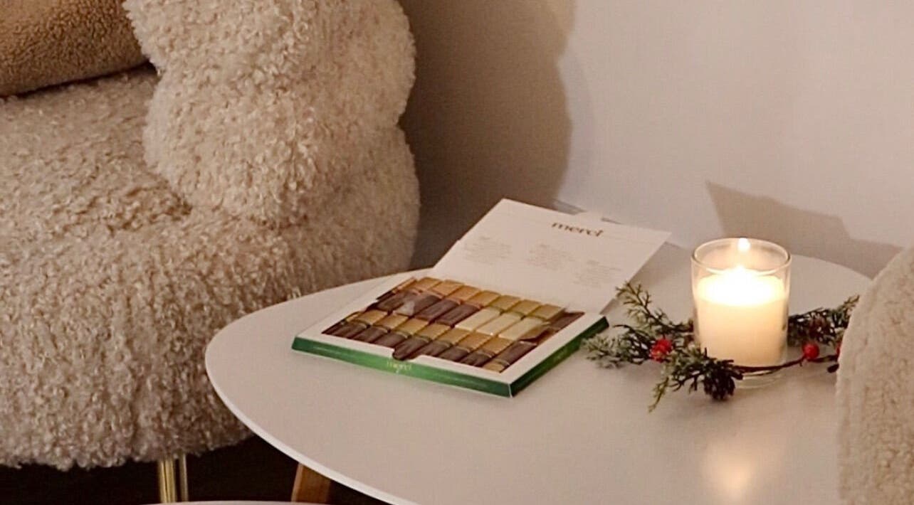 Udoban kutak u Rituals Nails, Beograd, RS s plišanom stolicom i svijećom na stolu.