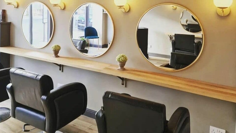 Stylish salon setup at The Little Hair Shop, Whittlesey, England, GB with sleek black chairs and circular mirrors.