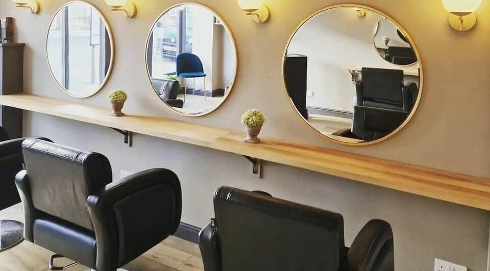 Stylish salon setup at The Little Hair Shop, Whittlesey, England, GB with sleek black chairs and circular mirrors.