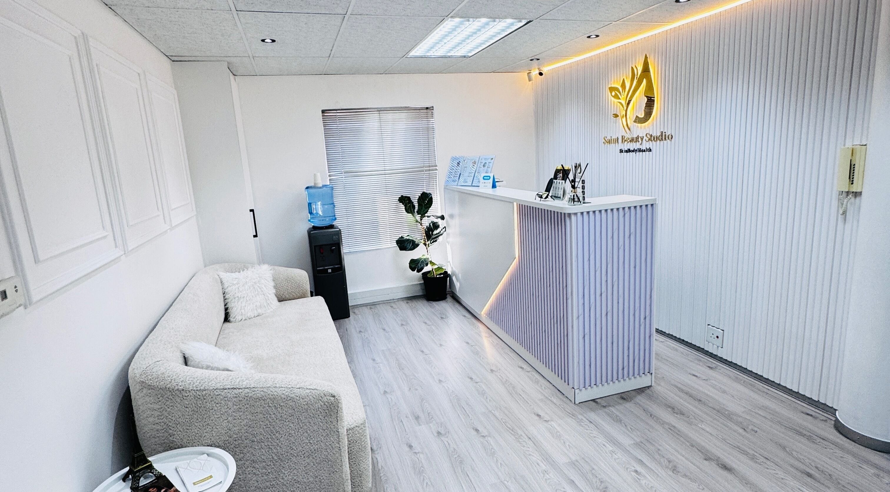 Reception area of Saint Beauty Studio in Sandton, Gauteng, ZA with a cozy couch and illuminated desk.