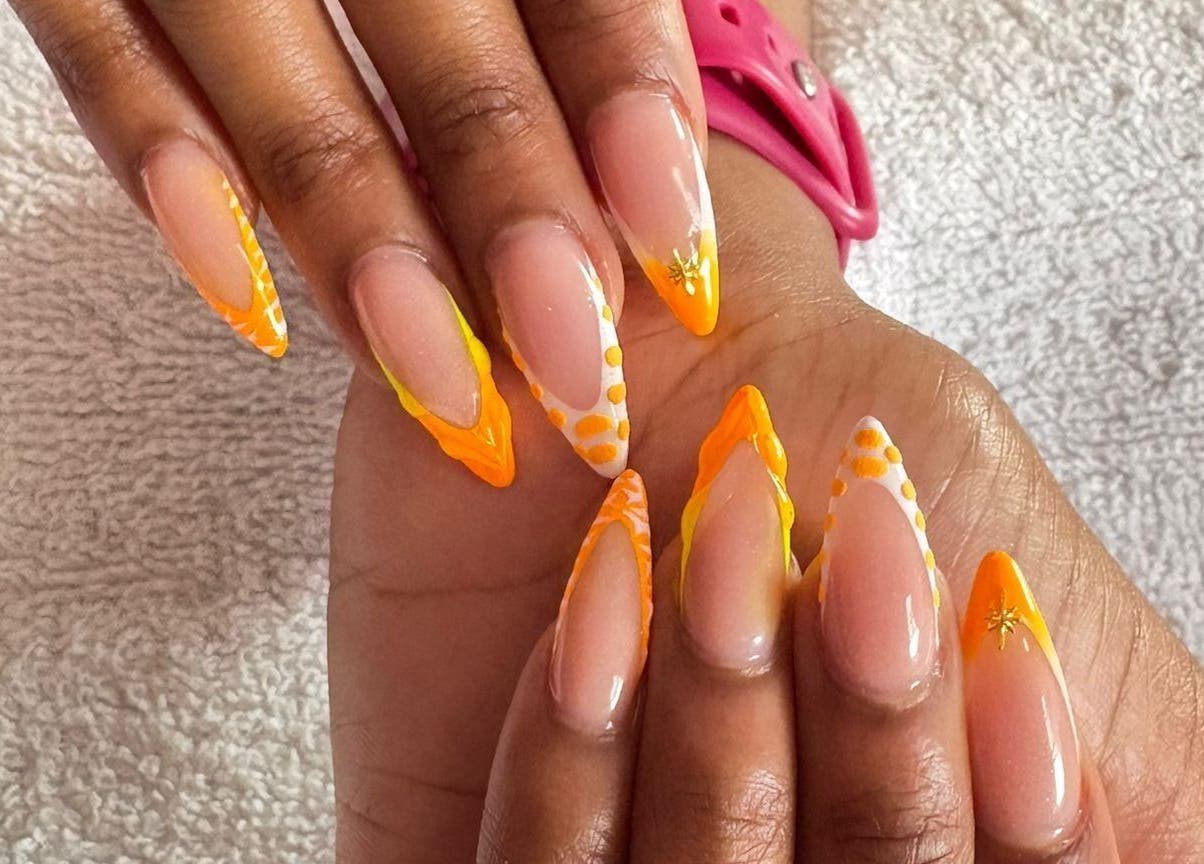 Vibrant nail art design at The StLucian Goddess Nail Salon, Gros Islet, LC featuring orange and yellow patterns.