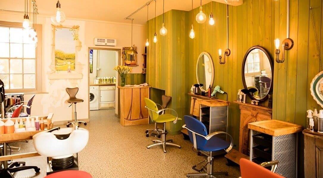 Warm, inviting interior of Natural Roots Salon in Glastonbury, England, GB with stylish chairs and mirrors.