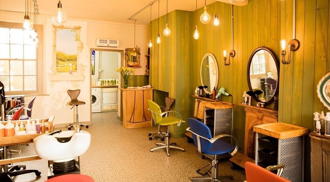 Warm, inviting interior of Natural Roots Salon in Glastonbury, England, GB with stylish chairs and mirrors.