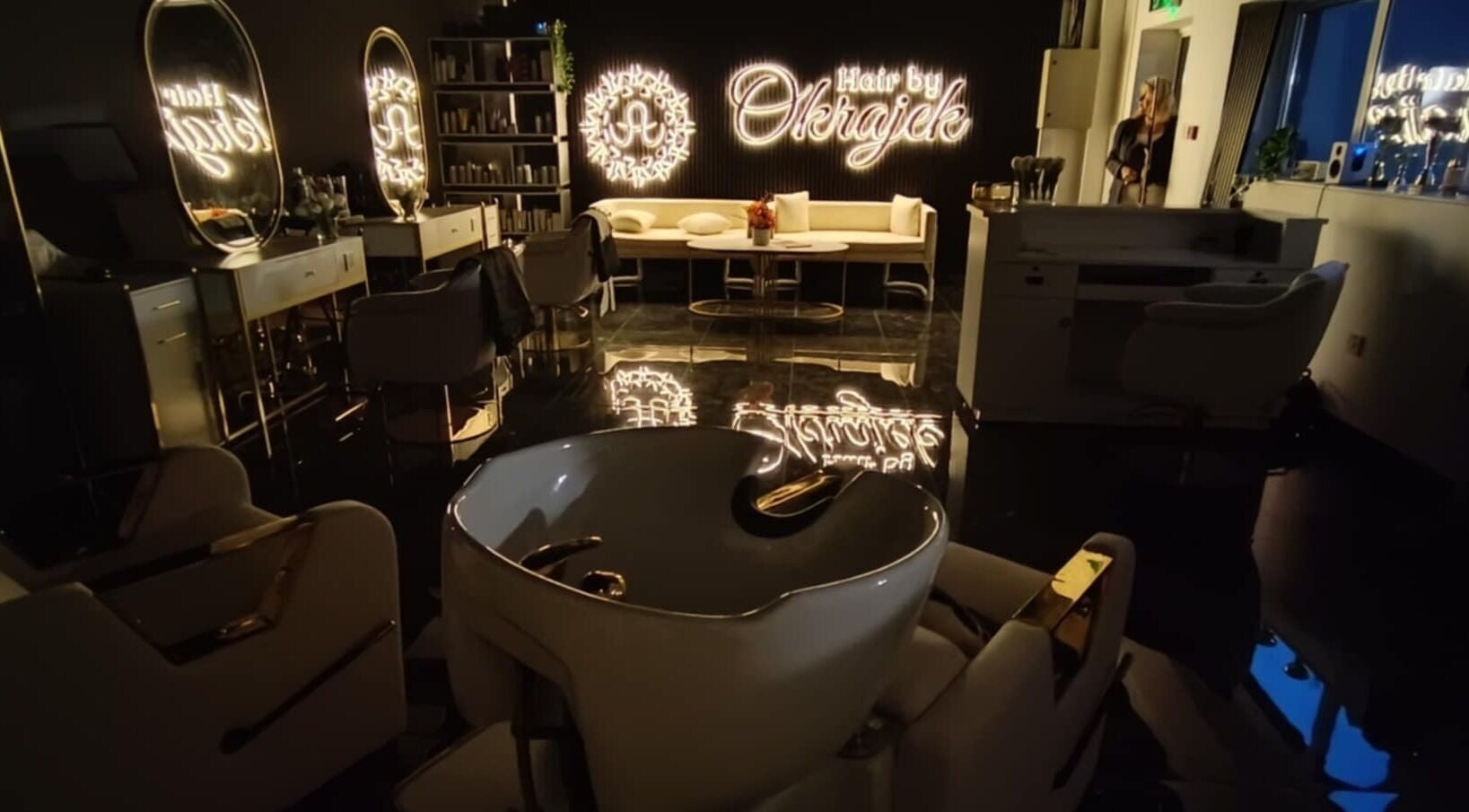 Elegant interior of Hair by Okrajek, Cork, County Cork, IE, featuring chic salon chairs and illuminated decor.