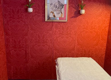 Cozy red wallpapered therapy room at Nifty Lash and Beauty in Hamilton, Waikato, NZ with artwork and plants.