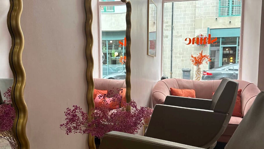 Stylish salon interior at Hairbyntash @ Shine Hair in Dundee, Scotland, GB with plush seating and large mirrors.