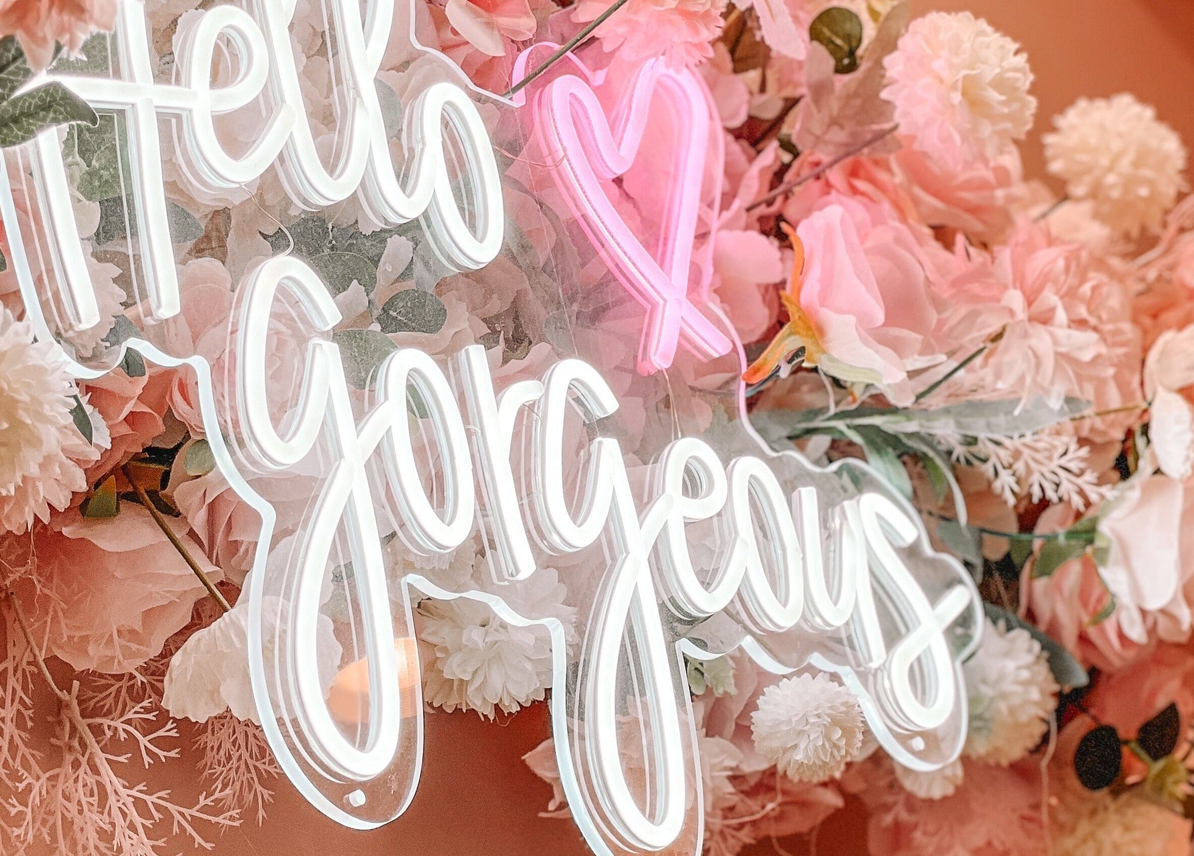 Neon 'Hello Gorgeous' sign surrounded by pink flowers at Glam Nails And Spa, Bowling Green, Kentucky, US.