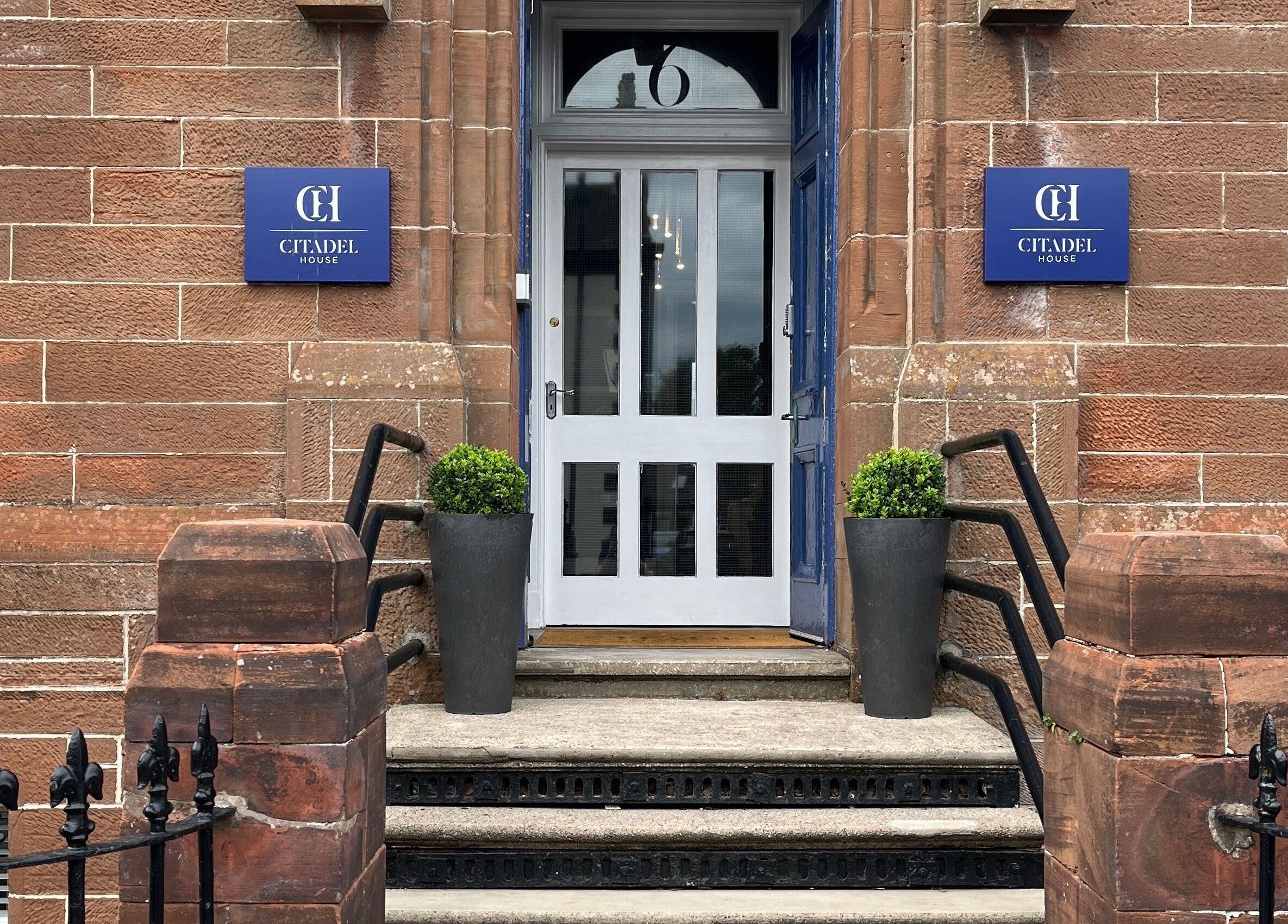 Entrance of Holistic Healthcare Ayrshire in Ayr, Scotland, GB showcases classic brick exterior and potted plants.