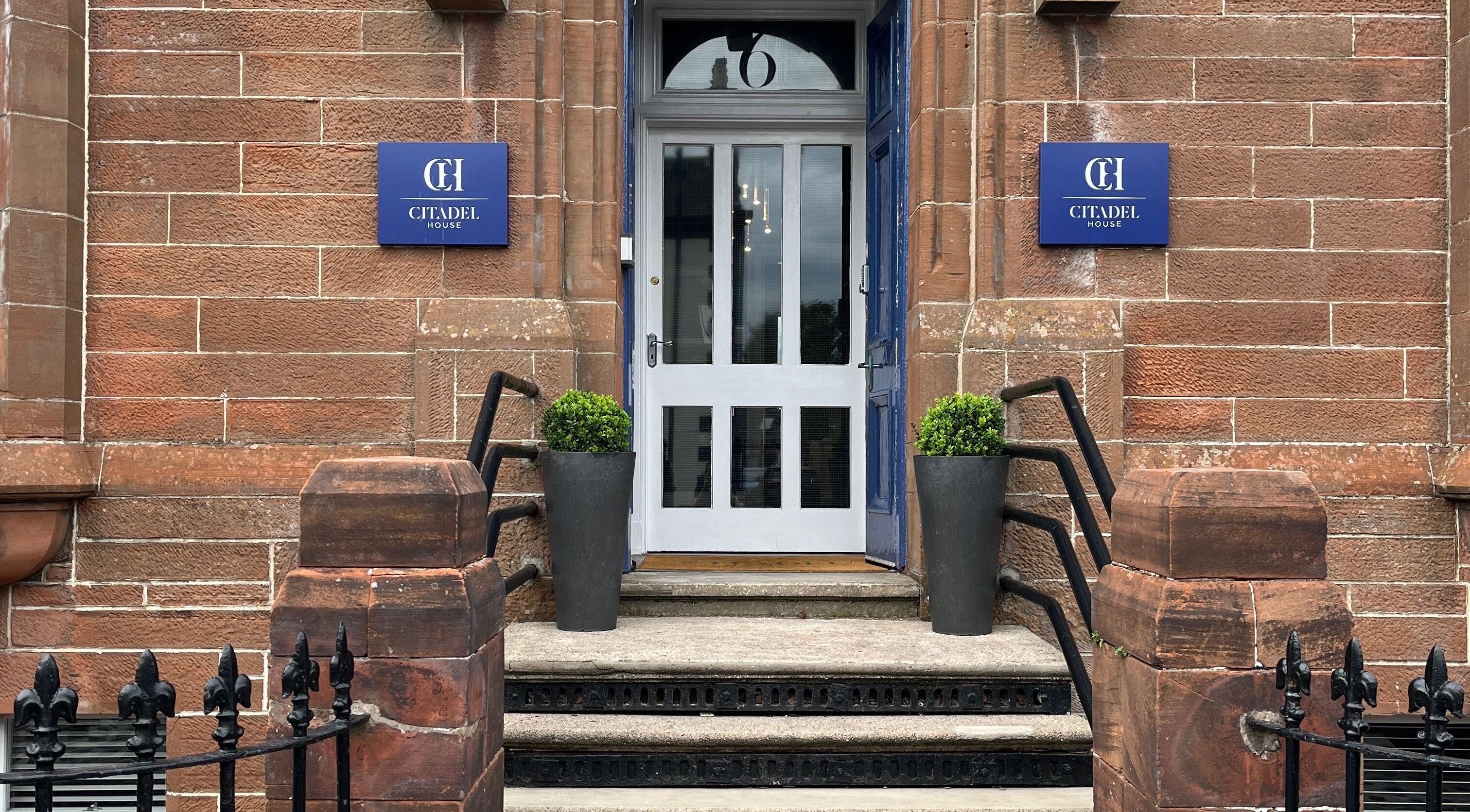 Entrance of Holistic Healthcare Ayrshire in Ayr, Scotland, GB showcases classic brick exterior and potted plants.