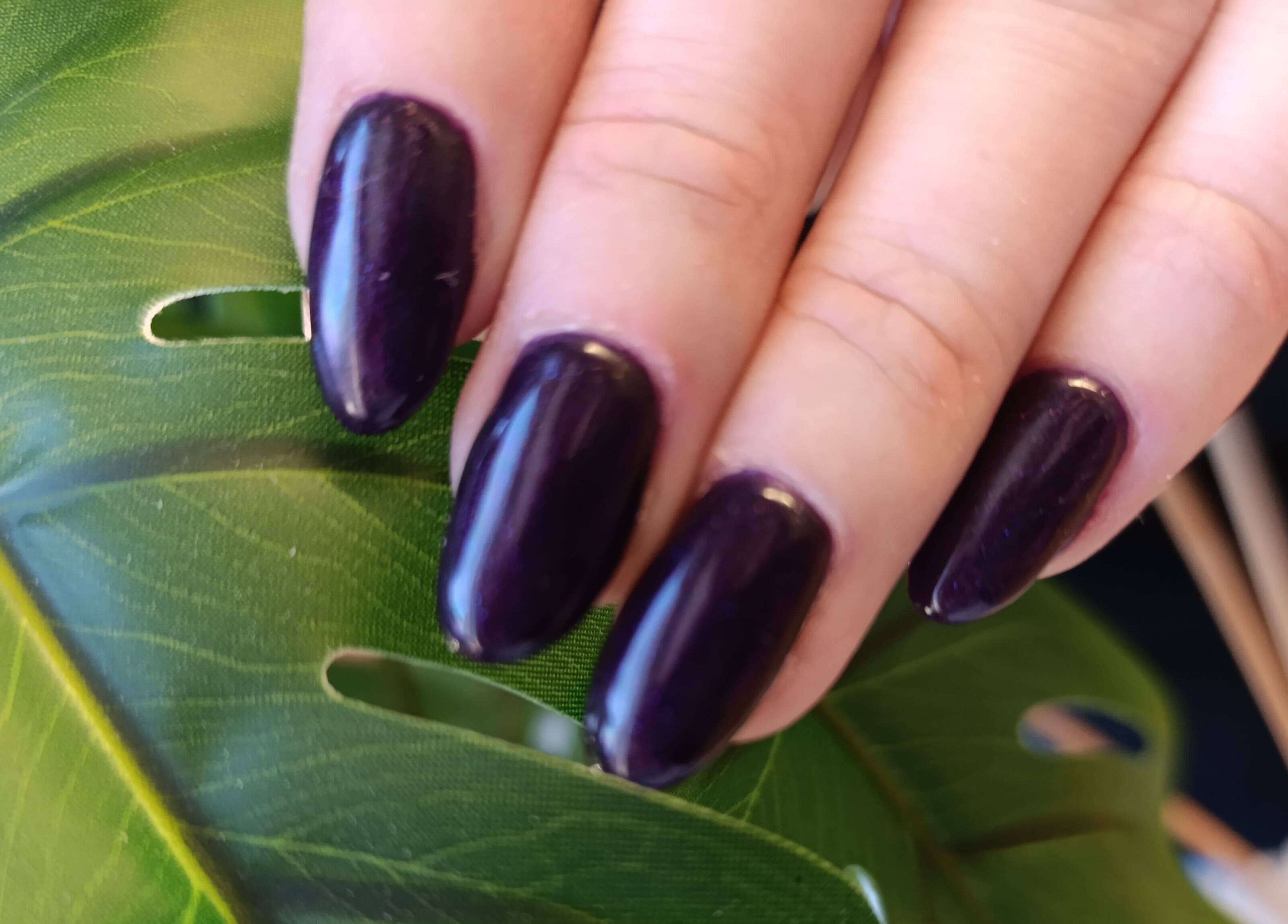 Elegant purple manicure at Oksi Nails Pärnu, Pärnu Maakond, EE, displayed against a green leaf.