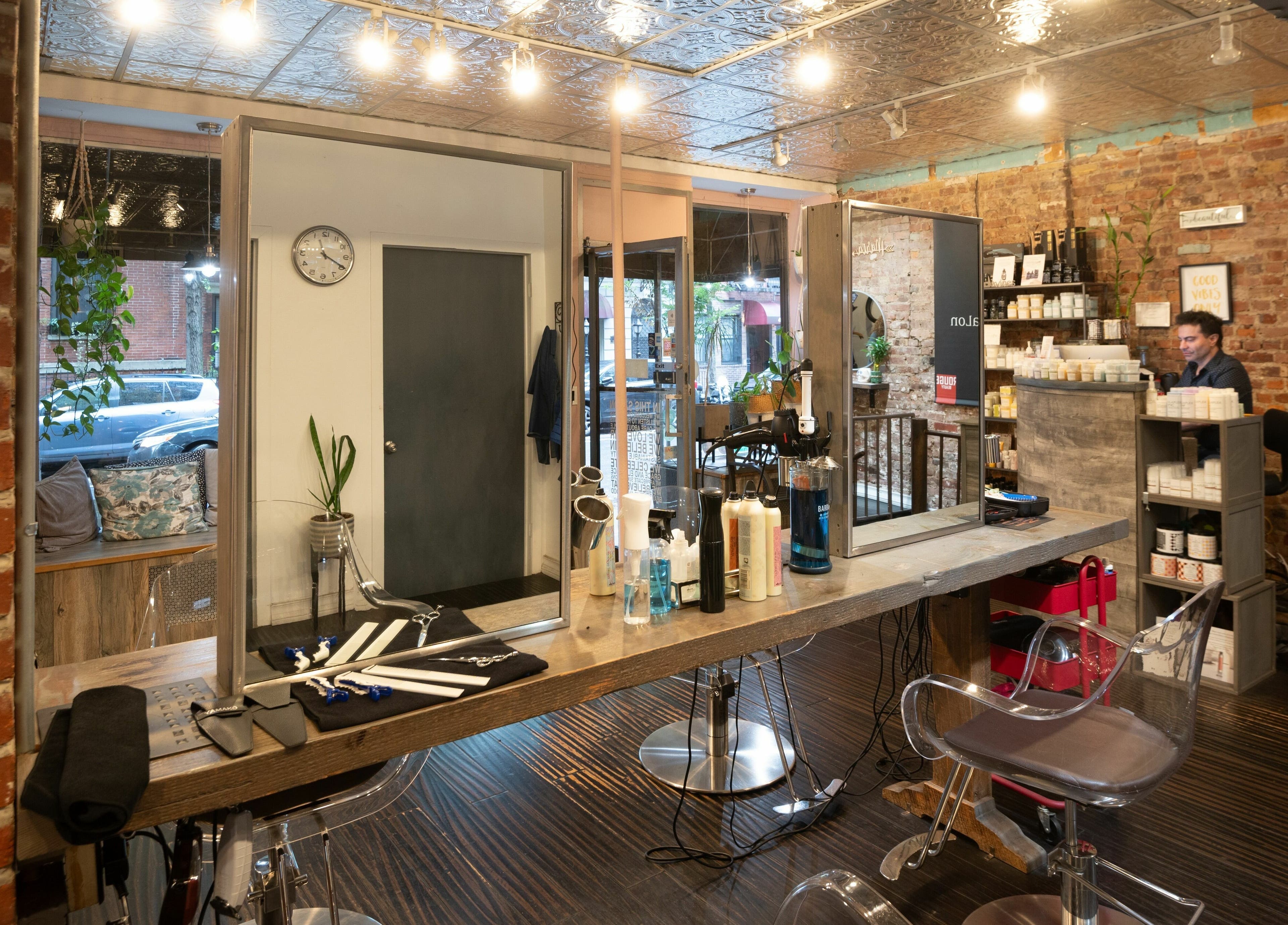 Elegant interior of David Ryan Salon in New York, New York, US with styling stations and brick walls.