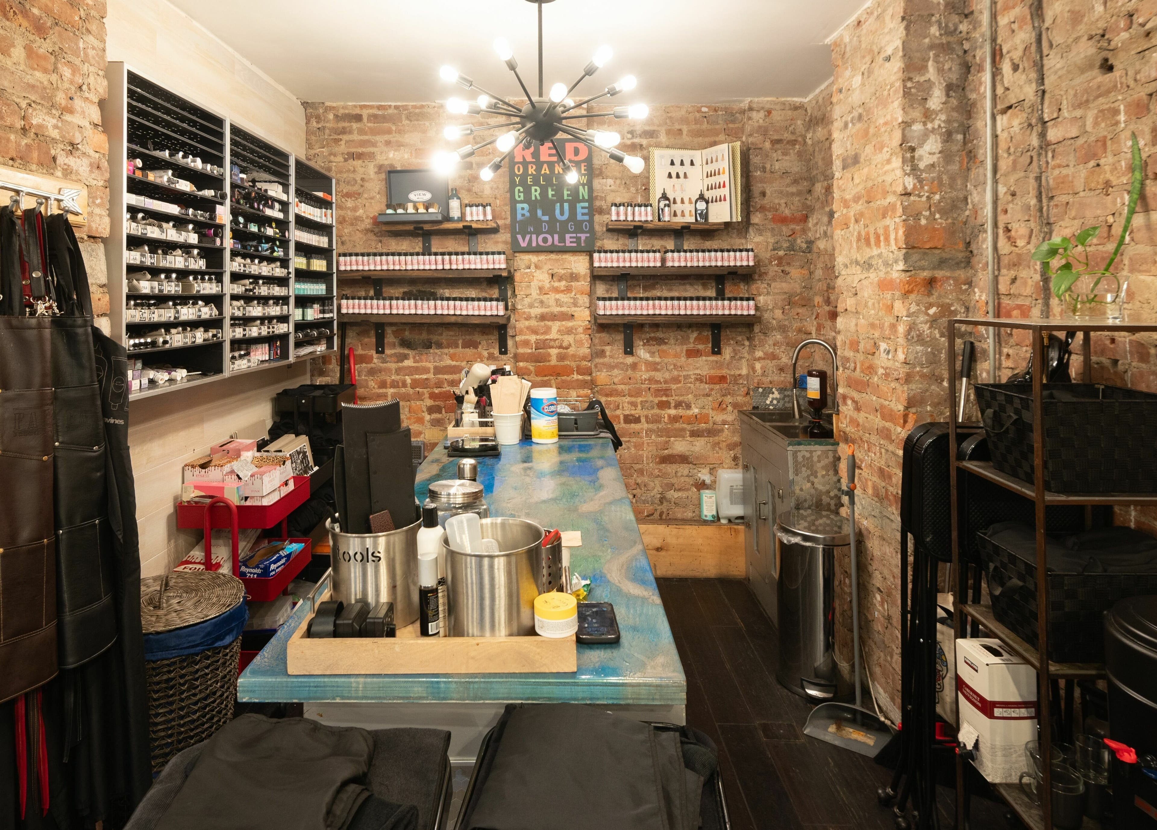 Interior of David Ryan Salon, New York, New York, US, featuring a stylish setup with brick walls and color supplies.