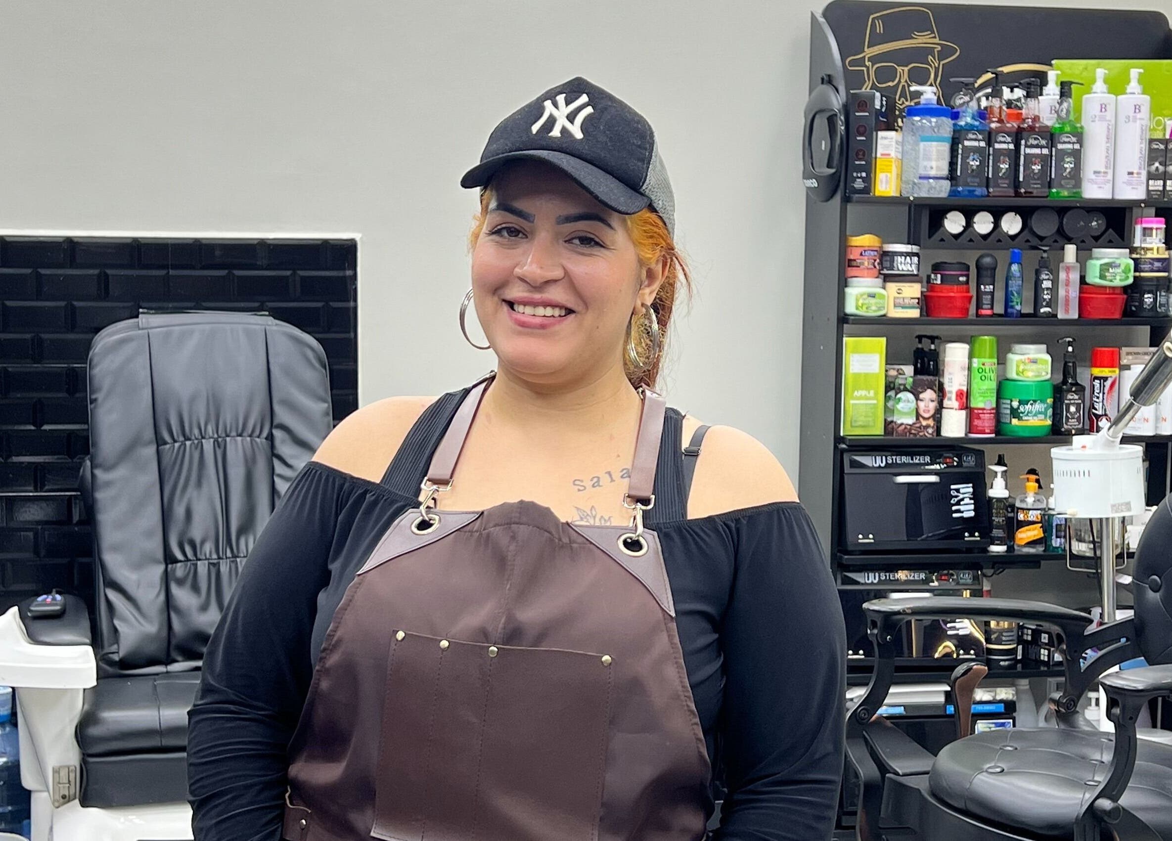 Smiling stylist at Glowing Gents Salon and SPA in Dubai, AE with professional salon chair and products.