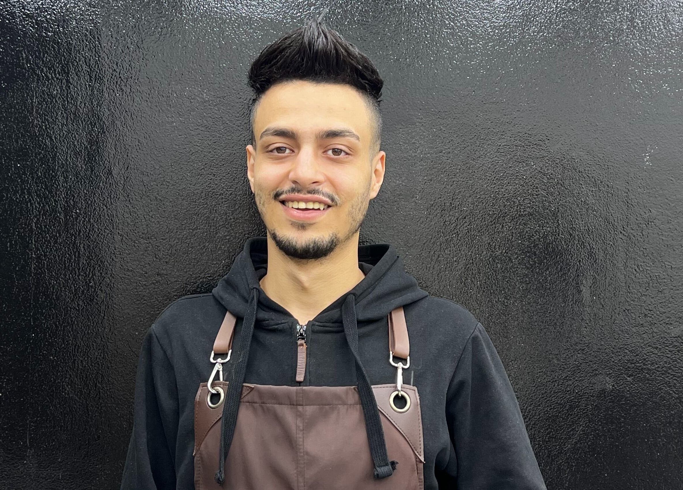 Friendly barber wearing apron at Glowing Gents Salon and SPA, Dubai, AE.