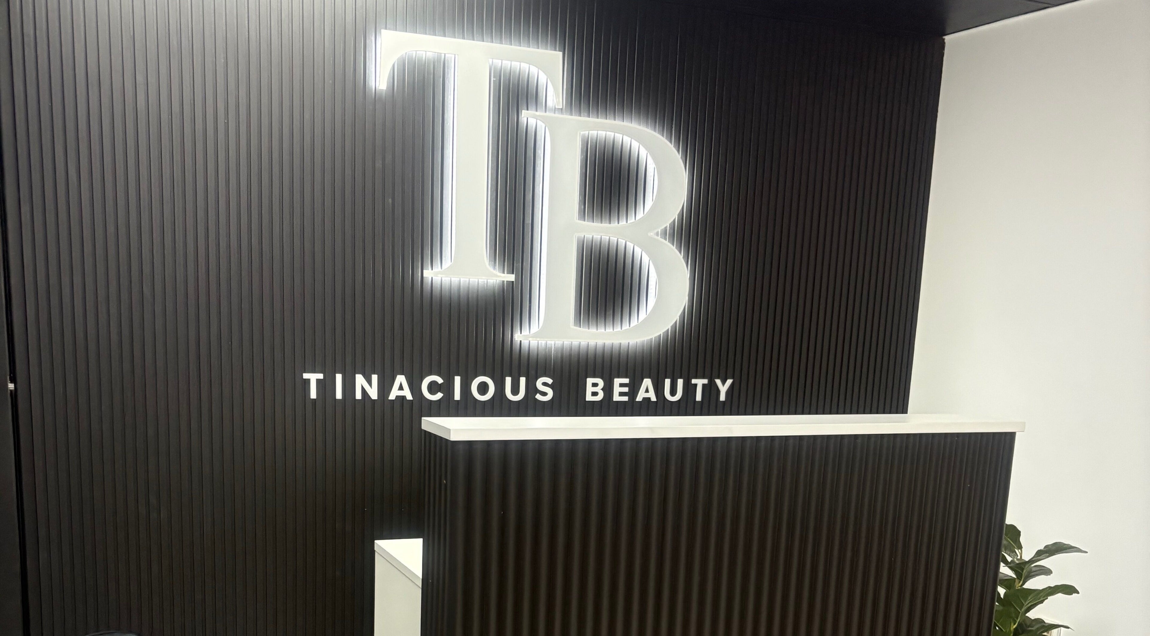 Front desk at Tinacious Beauty, Acacia Ridge, Queensland, AU with elegant black paneling and logo.
