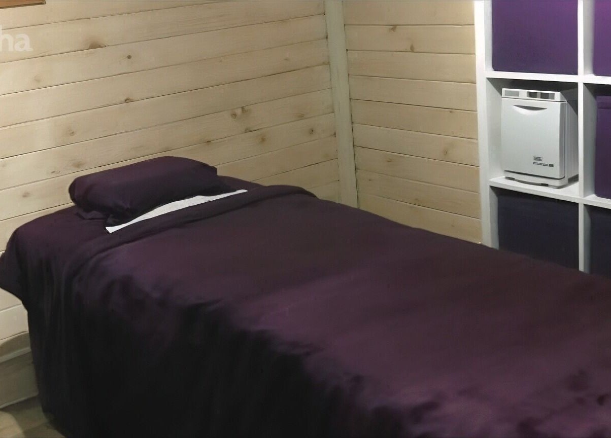 Cozy massage room at Nat-Rural Retreat, Vigo, England with purple sheets and wooden walls.