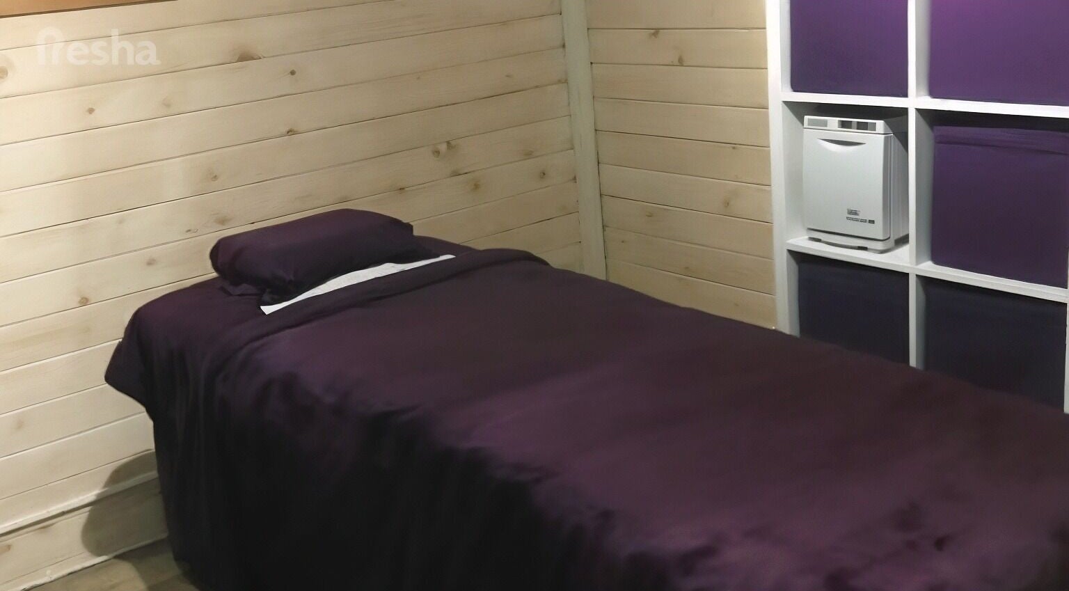 Cozy massage room at Nat-Rural Retreat, Vigo, England with purple sheets and wooden walls.