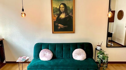 Interior acolhedor do Weilla Nail Studio em Lisboa, Lisboa, PT, com sofá verde elegante e arte icônica.