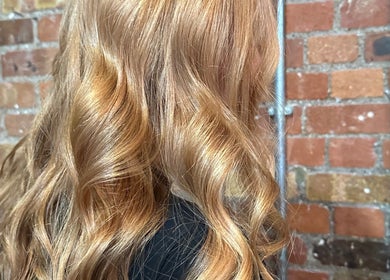 Luxurious golden curls styled at boo.colourist - East London, London, England, GB against a rustic brick backdrop.
