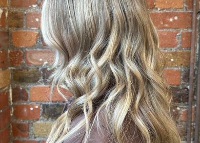 Wavy blonde hair styled at boo.colourist - East London, London, England, GB, against a brick wall backdrop.