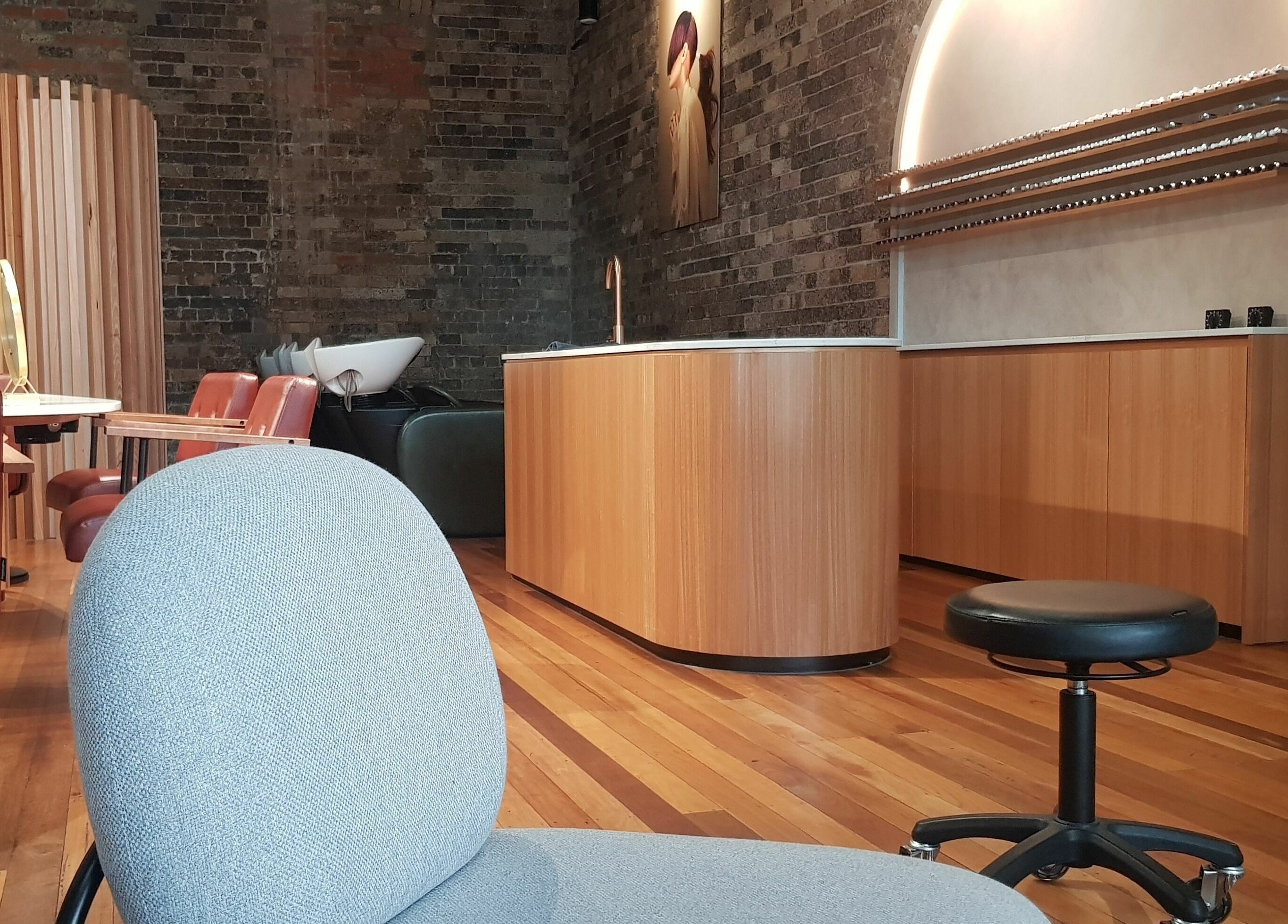 Elegant salon decor at Ella&Jade Woolloongabba, Queensland, AU with wooden furnishings and exposed brick.