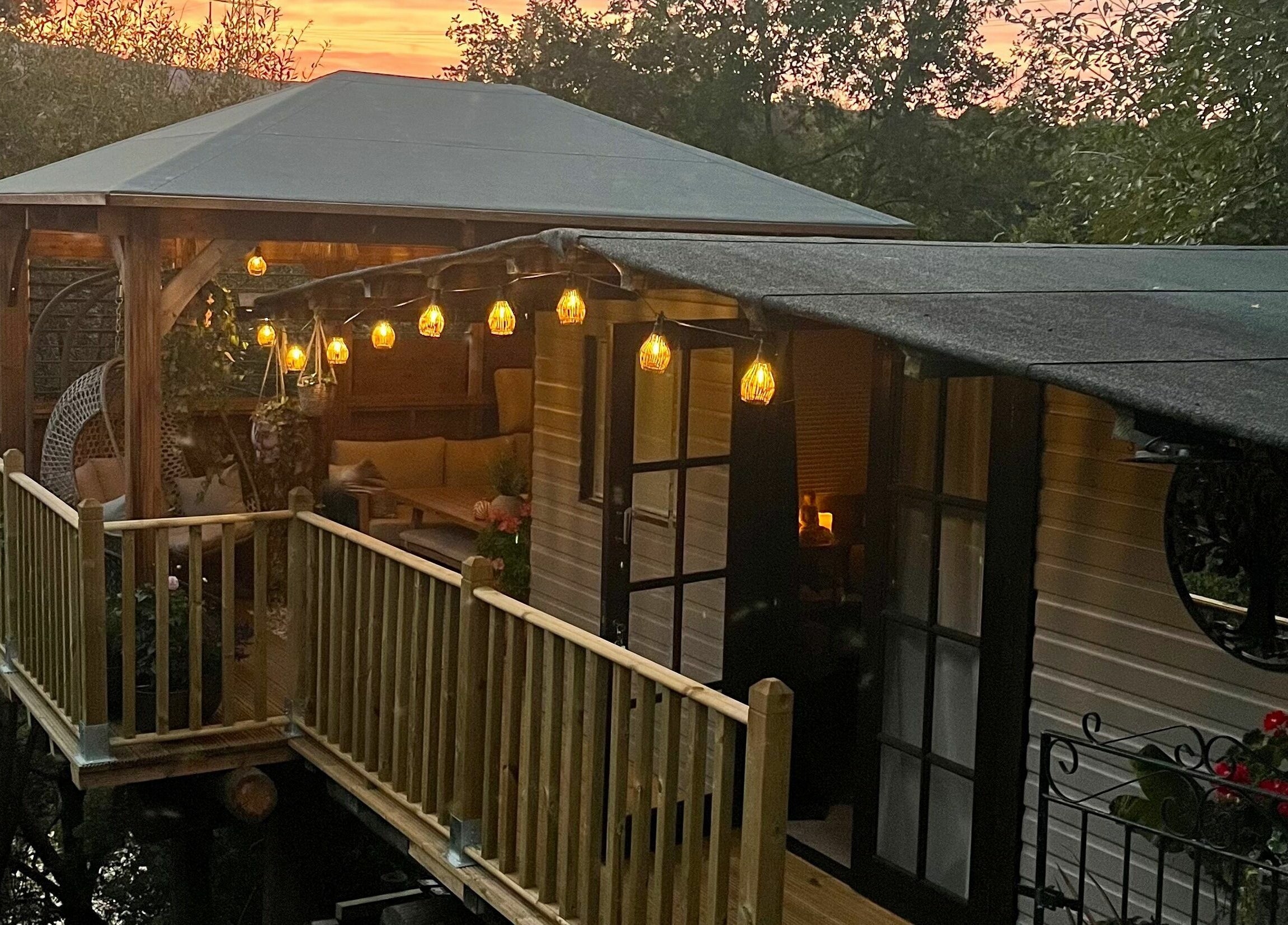 Beautiful sunset view of Tranquility Treatment Room's cozy deck in Whitworth, England, GB with hanging lights.
