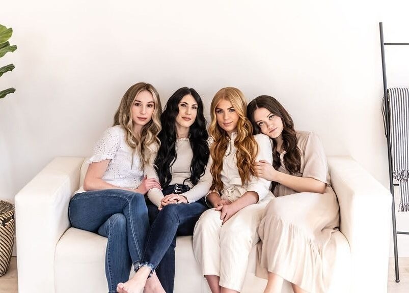 Four women at La Belle Vie Salon and Spa, Pleasant Grove, Utah, US, showcasing diverse hair styles on a white sofa.