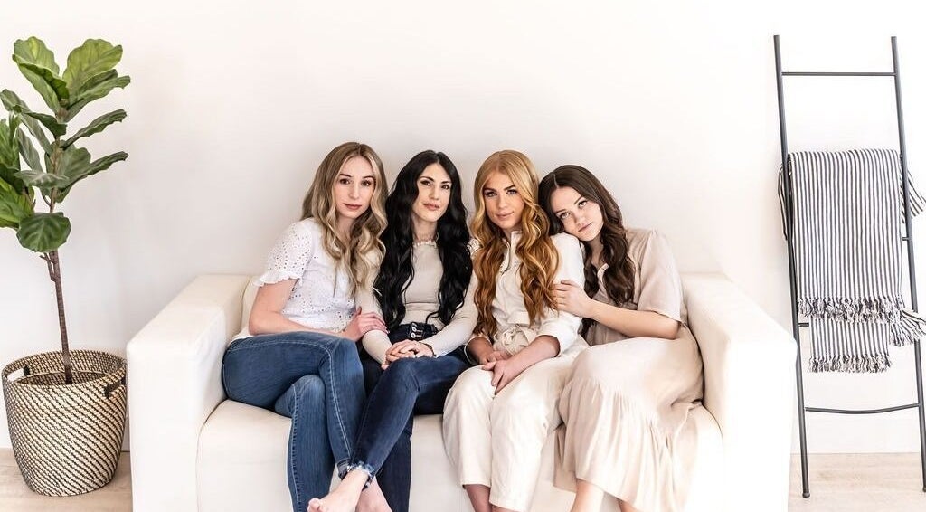 Four women at La Belle Vie Salon and Spa, Pleasant Grove, Utah, US, showcasing diverse hair styles on a white sofa.
