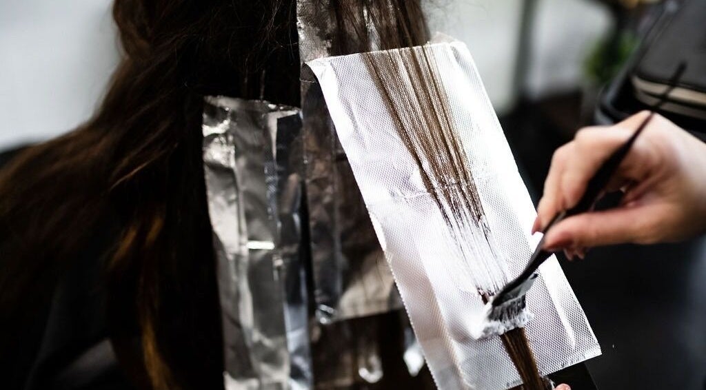 Hair coloring process at West Ivie Collective Beauty Lounge in Lindon, Utah, showcasing expert touch with foils.