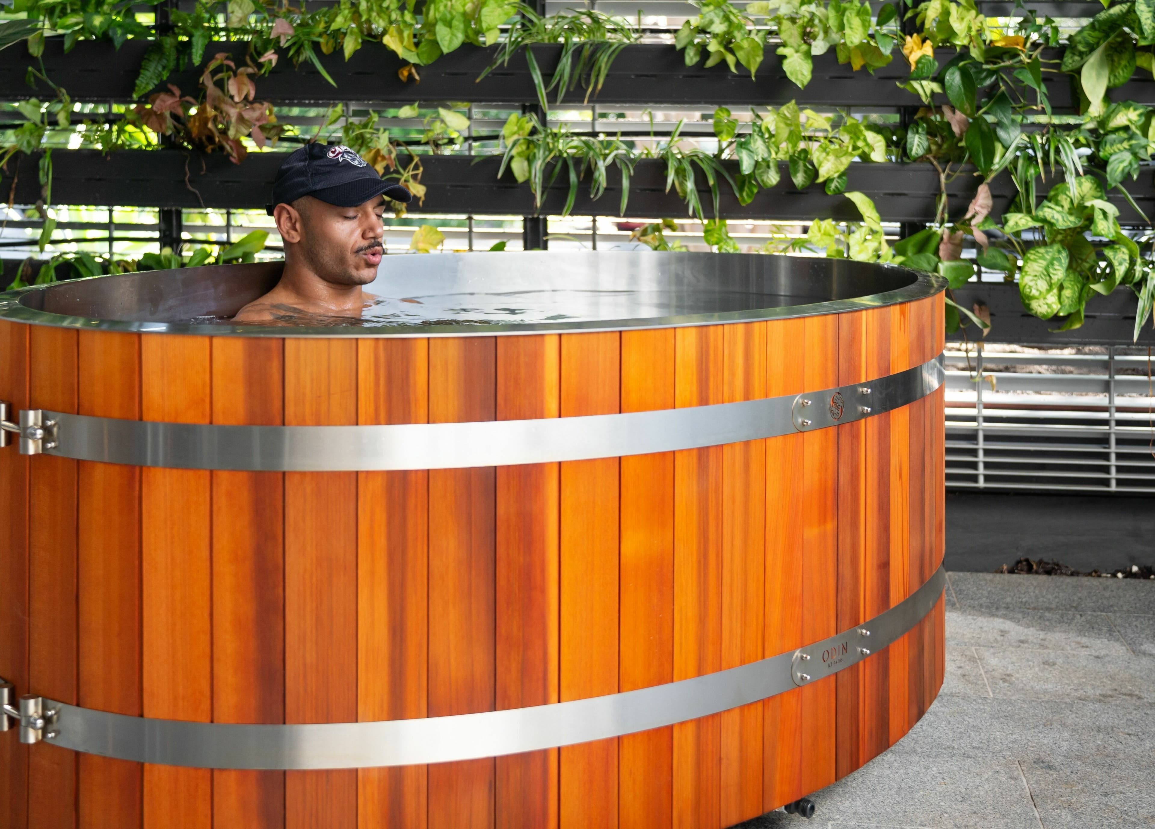 Man relaxing in outdoor wooden hot tub at Recovery Room Seaspray, Zilzie, Queensland, AU, surrounded by plants.