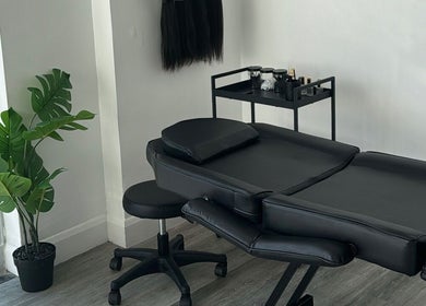 Elegant treatment room at Brooke Paris studios, London, England, GB, featuring black massage table and greenery.
