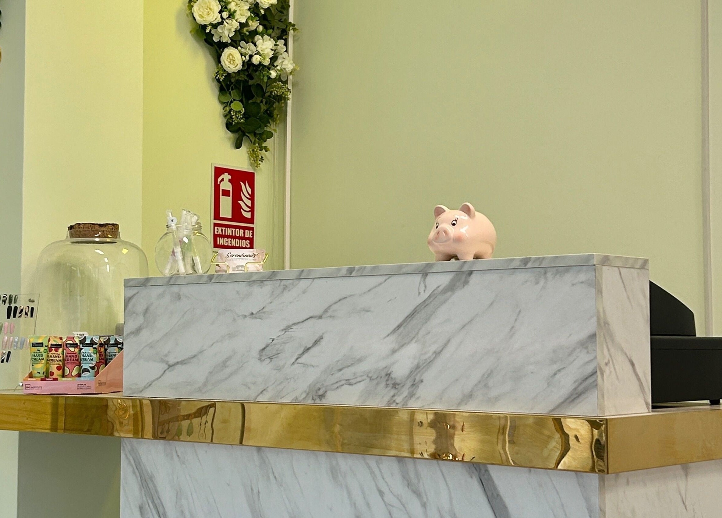 Mostrador de mármol en Serendinails, Alcorcón, Comunidad De Madrid, ES, con decoraciones florales y muestras de uñas.